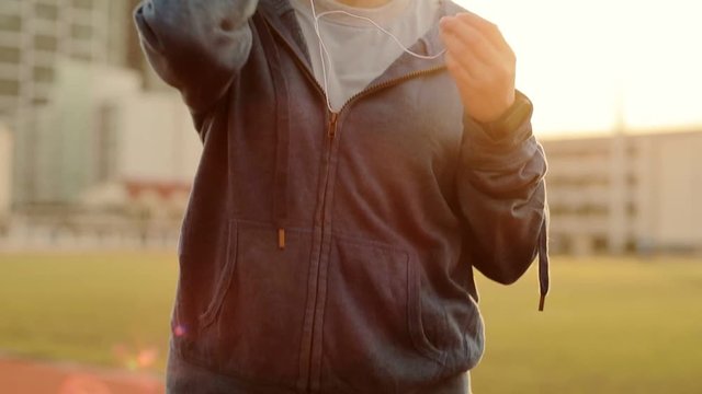Young women puts the earphones on before run workout standing  sport stadium.