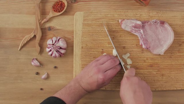 Cook cuts garlic cooks raw steak seasonings food table top still life man hands knife slice