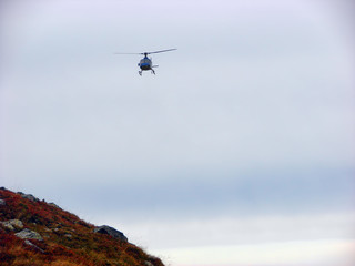 Fototapeta na wymiar Helicopter flying above the mountain