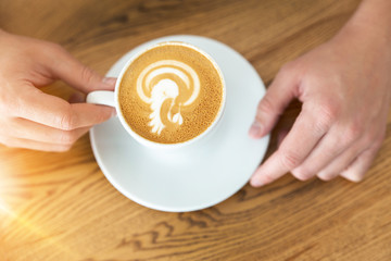 man holding cup of hot coffee with art pattern , closeup, wooden background