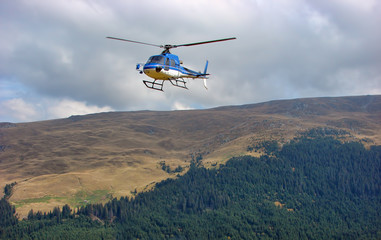 Blue helicopter above the forest