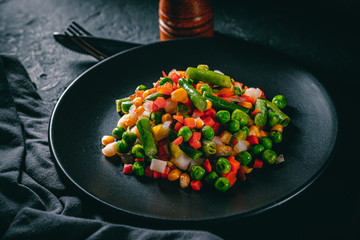 Mixed vegetables on a black plate on Dark grey black slate background