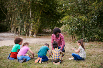 Obraz premium Team Leader Showing Group Of Children On Outdoor Camping Trip How To Make Fire