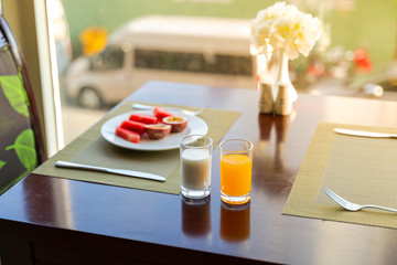 Fototapeta na wymiar Fresh romantic breakfast table next to window with dessert foods: fruits, juice and milk
