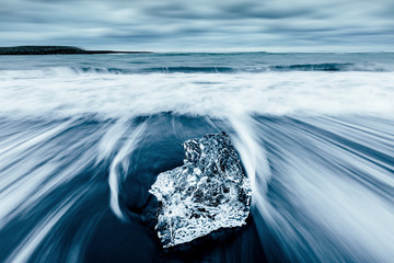 Incredible pieces of the iceberg sparkle on black sand. Location Jokulsarlon lagoon, Diamond beach, Iceland, Europe.