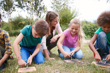 Female Team Leader Showing Group Of Children On Outdoor Camping Trip How To Make Fire