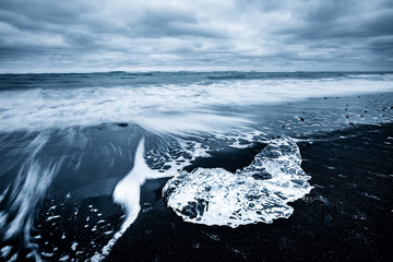 Incredible pieces of the iceberg sparkle on black sand. Location Jokulsarlon lagoon, Diamond beach, Iceland, Europe.