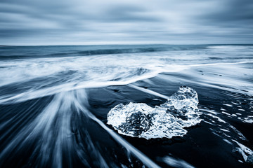 Incredible pieces of the iceberg sparkle on black sand. Location Jokulsarlon lagoon, Diamond beach, Iceland, Europe.