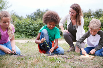 Female Team Leader Showing Group Of Children On Outdoor Camping Trip How To Make Fire