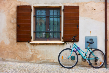 Fototapeta na wymiar Bicycle in the street near wall of old house