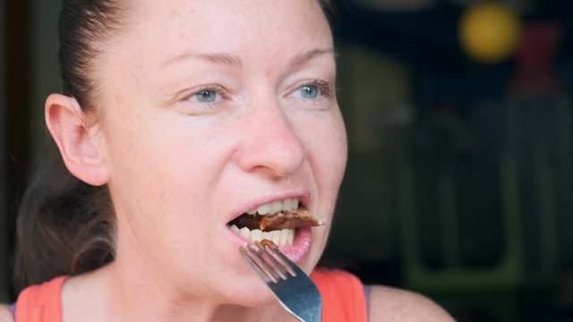 Portrait of woman eating meat carefully chewing piece of beef steak.