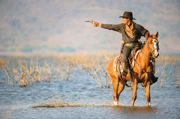 Cowboy on horseback on water and mountain background