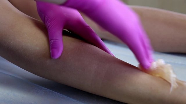 azulene depilation. wax hair removal, shugaring. concept of smooth skin without hair. azulene color. the master puts azulene on the girls legs