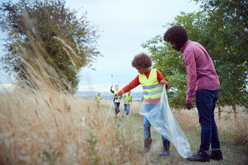 Adult Team Leader With Group Of Children At Outdoor Activity Camp Collecting Litter Together