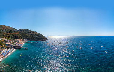 Fototapeta na wymiar Aerial view of rocky beach, coastline of the village of Nerano. Private and wild beaches of Italy. Turquoise, blue surface of the water. Vacation and travel concept. Boats on raid. Copy space