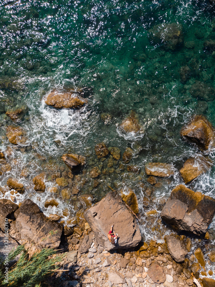 Sticker Top down aerial view of rocky beach, coastline of the village of Nerano. Wild beach of Italy. vertical photo. Vacation and travel concept. Two people, couple of tourists is sitting on rock.