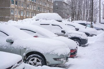 Cars buried under a thick layer of snow after a blizzard in a basement area