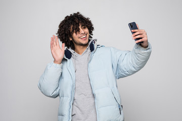 Young curly man make video call with phone isolated on white background