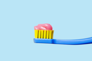 Bright toothbrush with pink paste close-up on a blue background.