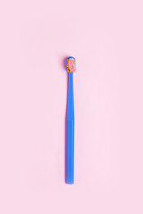 Bright toothbrush with pink paste on a pink background.