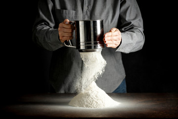 hands with flour working in the kitchen on the wooden table splash