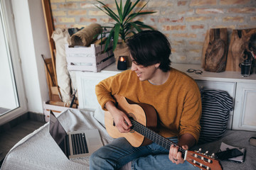 young man playing guitar at home