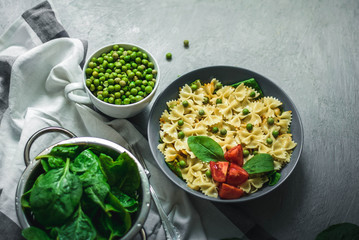  pasta with green peas and tomatoes on a gray background with veneer sheet