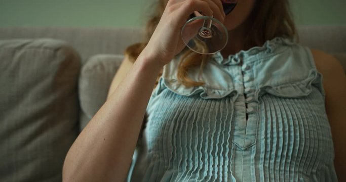 Pregnant woman drinking a glass of wine on the sofa