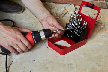 sets the Drill bit in the drill,hands take the drill bit and install in the electric drill