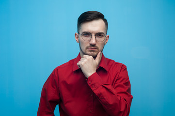 Pensive Young man in glasses and a burgundy shirt