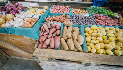 Heap of raw produces potatoes, sweet potatoes, green garlic, onion at market stand in Puyallup, WA