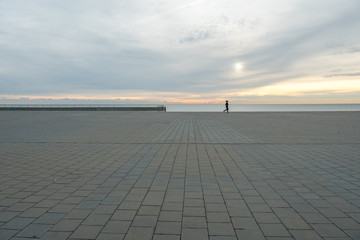 Hombre caminando al amanecer con mar y cielo de fondo. Barcelona, España	