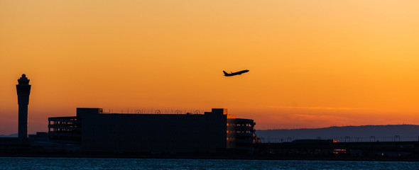 セントレアの夕景・オレンジ色の空と管制塔と離陸する飛行機のシルエット