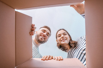 Young couple looking inside cardboard box, bottom view