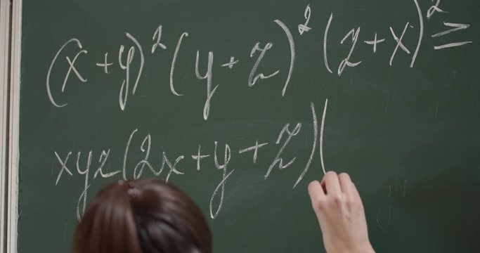Student hand writing math formula on chalkboard, school lessons, education