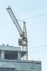 Construction site background. Hoisting crane and new multi-storey building. Industrial background.