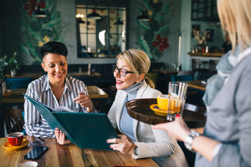 women looking at the menu and ordering food at the restaurant