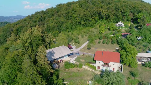 Houses connected by winding roads in a lush green mountain landscape. Drone flyby aerial view.