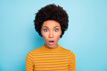 Close up photo of pretty dark skin curly lady listen awful news open mouth unexpected epic fail wear yellow striped sweater isolated blue color background