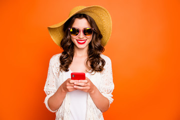 Photo of funny lady summer time holding telephone sending best friend photos from tropical ocean resort wear sun hat specs stylish beach cape isolated orange background - obrazy, fototapety, plakaty