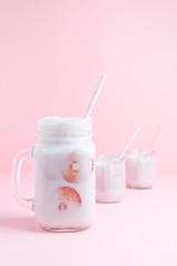Strawberry milk shake with strawberry pieces in a jar on a pastel pink background. Healthy food