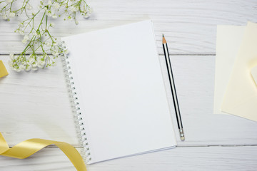 Blank notebook with pencil on white wooden background. Flat lay composition with free space for...