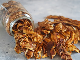 Dried melon chips in a glass jar on a wooden background. Home cooking. Natural healthy product, place for text.