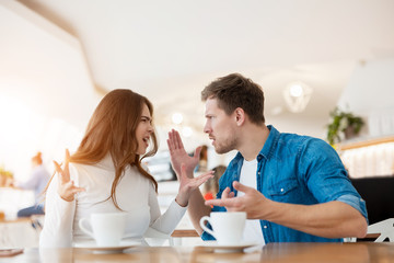 young couple beautiful woman and handsome man fighting, having argument while drinking coffee in cafe during lunch time break, problematic relationships concept