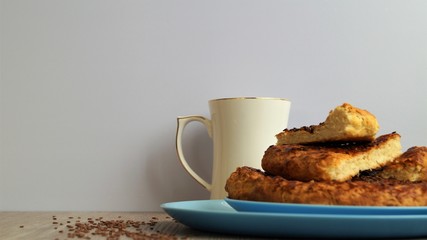 oriental bread on a blue dish with white porcelain mug and linen seeds on a wooden table on white background