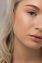 Closeup of half beauty woman with clean skin and natural cosmetics. Beautiful extrem eyelash and full lips of well-groomed girl demonstrate spa procedures, injections in a beauty parlor. Blonde hair