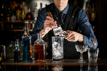 Barman with special device breaks pieces of ice to make a cocktail.