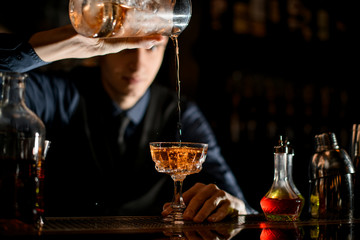 Close-up as bartender fills a wineglass with a cocktail.