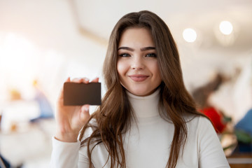 young brunette woman holding bank card looking satisfied, banking concept