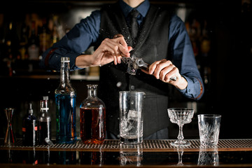 Bartender splits pieces of ice to make a cocktail.